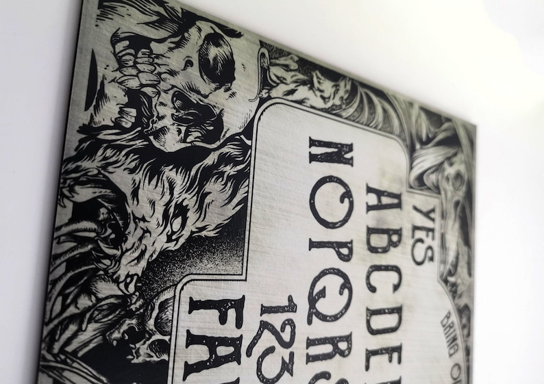 May include: A silver and black Ouija board with a skull and wolf design. The board features the letters A-Z, numbers 1-9, and the words "YES", "NO", and "GOODBYE".