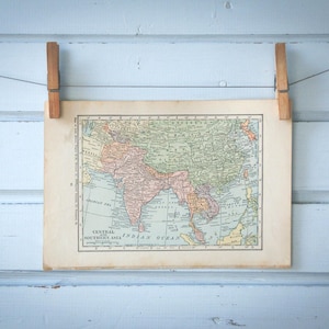Könnte beinhalten: Eine Vintage-Karte von Zentral- und Südasien, gedruckt auf Papier und an einer hellblauen Wand mit Holz-Wäscheklammern aufgehängt.