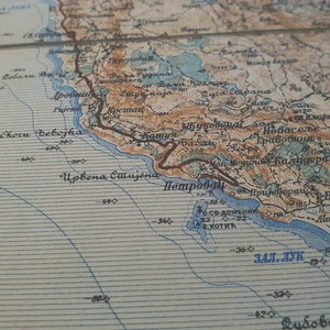 May include: A detailed vintage map with a coastal region, featuring shades of brown, blue, and beige. The map includes geographical features, place names, and contour lines, suggesting a historical or antique cartographic piece.