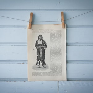 Può includere: Un'illustrazione in bianco e nero di un uomo nativo americano con un copricapo piumato e che tiene un fucile. L'illustrazione è stampata su una pagina di un libro con testo in tedesco.