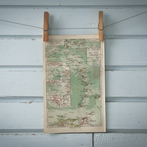 Op de afbeelding: Een vintage kaart van de Kleine Antillen, gedrukt op papier en hangend aan een lichtblauwe houten muur met twee houten wasknijpers.