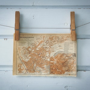 Puede incluir: Un mapa antiguo y vintage de Reichenberg, Bohemia, colgado en una pared de madera blanca con dos pinzas de madera.