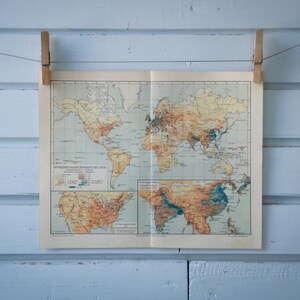 Può includere: Una mappa del mondo vintage stampata su carta, appesa a un muro blu chiaro con mollette di legno.