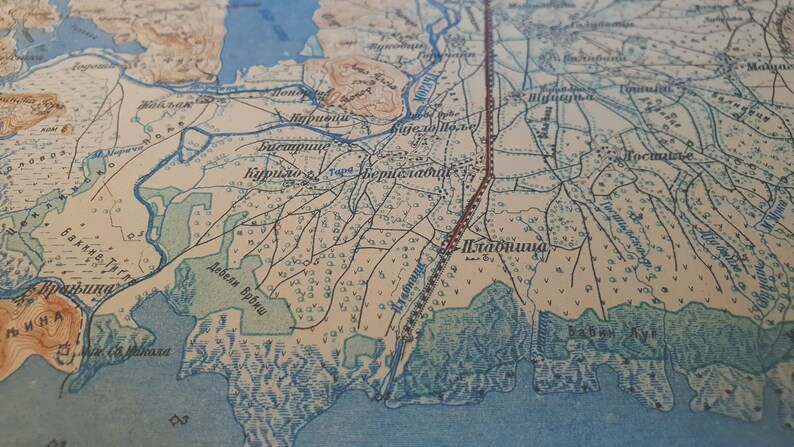 May include: Antique map with detailed cartography. The map features a network of rivers, roads, and settlements, with text labels in a foreign language. The color palette includes shades of beige, blue, and brown, giving it a vintage aesthetic.