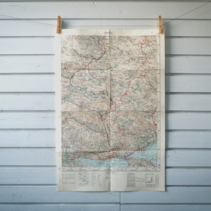 Puede incluir: Un mapa vintage de una región cuelga de una pared de madera blanca con dos pinzas de madera.
