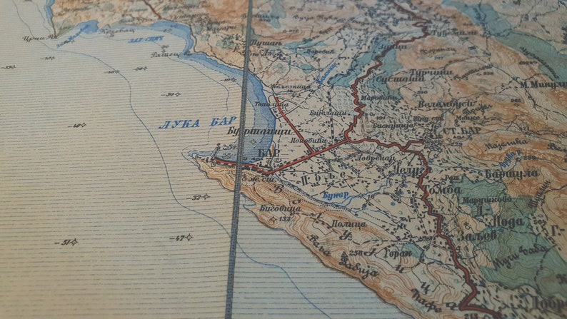 May include: Vintage map with text in a foreign language, featuring coastal regions and geographical details. The map has a faded, aged appearance with blue, brown, and beige tones. The text includes the words "ЛУКА БАР" and "СТ. БАР".