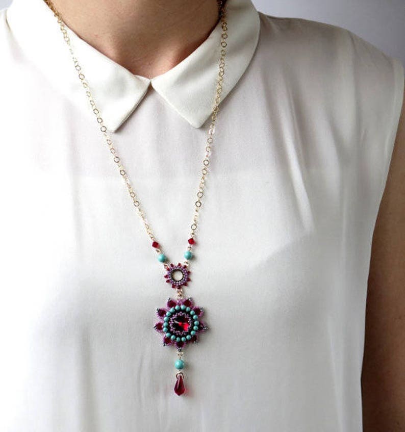 May include: A gold chain necklace with a turquoise and red beaded pendant featuring a flower design.
