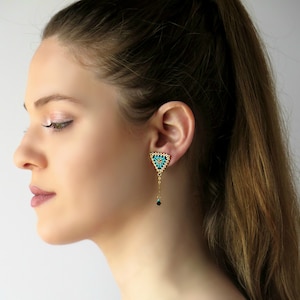 May include: A pair of gold triangle earrings with turquoise and black beads. The earrings are dangling and have a geometric design.