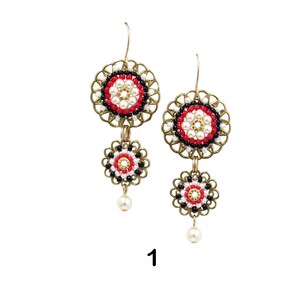 May include: A pair of gold tone earrings with red, white, and black beaded circles. The earrings have a dangling pearl at the bottom.