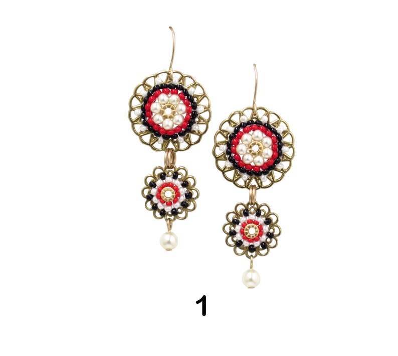 May include: A pair of gold tone earrings with red, white, and black beaded circles. The earrings have a dangling pearl at the bottom.