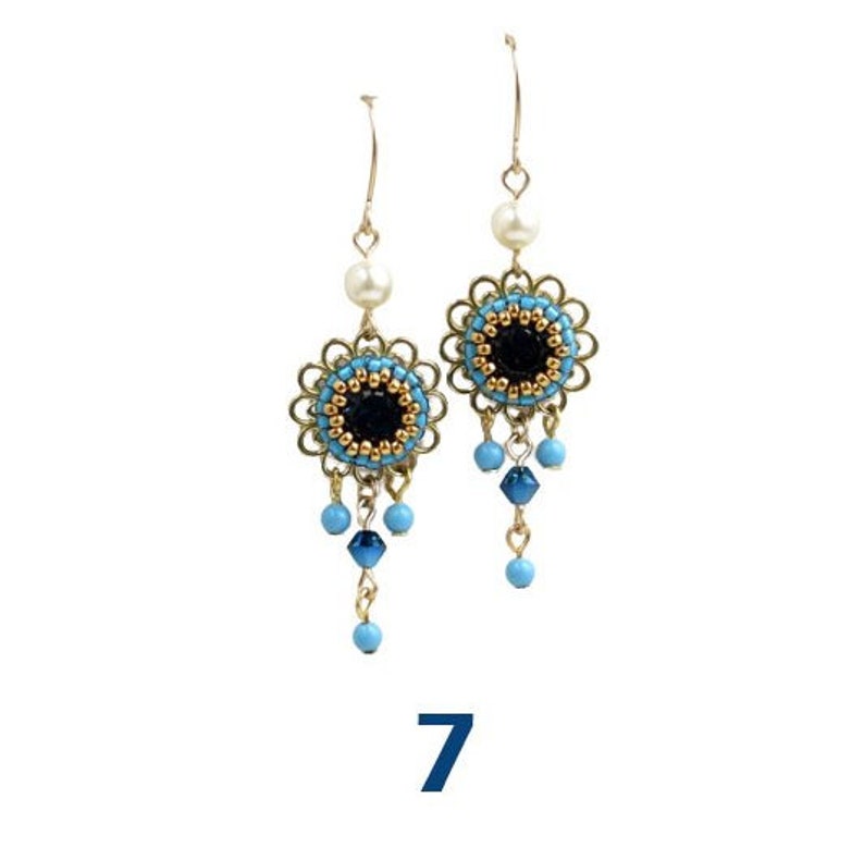 May include: A pair of gold dangle earrings with blue and black bead accents. The earrings feature a round, beaded design with a black center and a gold rim. The beads dangle from the center of the round design.
