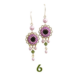 May include: A pair of dangle earrings with a pink and green beaded flower design. The earrings have a gold tone and are accented with small pink and green beads.