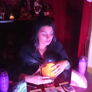 Warm, natural-light portrait of Psychic Amanda in her dedicated spiritual space, surrounded by shelves of esoteric books, crystals, and tarot decks.