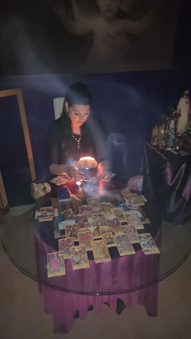 Warm, natural-light portrait of Psychic Amanda in her dedicated spiritual space, surrounded by shelves of esoteric books, crystals, and tarot decks.