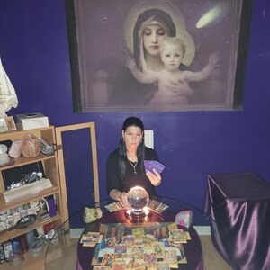 Photo of Psychic Amanda carefully writing down intuitive insights for a written PDF report, with crystals and burning candles neatly arranged on her desk.