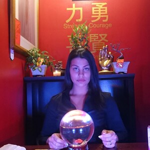 Portrait of Amanda sitting at her reading table with her hands gently resting near a glass crystal ball, ready to connect with intuitive energy.