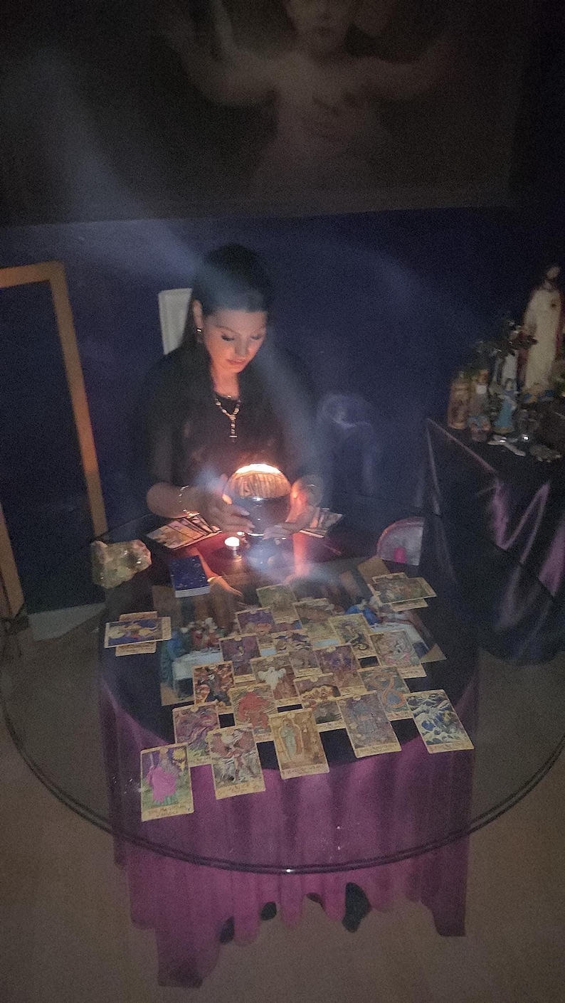 Photo of Psychic Amanda carefully writing down intuitive insights for a written PDF report, with crystals and burning candles neatly arranged on her desk.