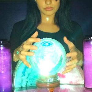 Portrait of Amanda sitting at her reading table with her hands gently resting near a glass crystal ball, ready to connect with intuitive energy.
