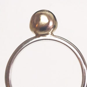 K&ouml;nnte beinhalten: Ein silberner Ring mit einer goldenen Kugel oben drauf.