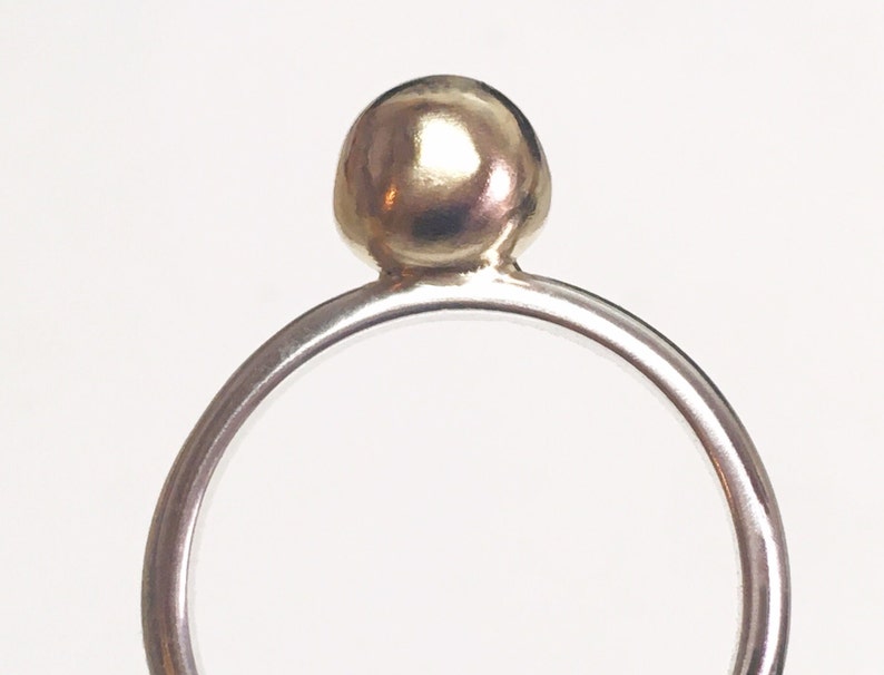 K&ouml;nnte beinhalten: Ein silberner Ring mit einer goldenen Kugel oben drauf.