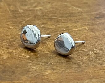 May include: A pair of silver stud earrings with a hammered, irregular oval shape.