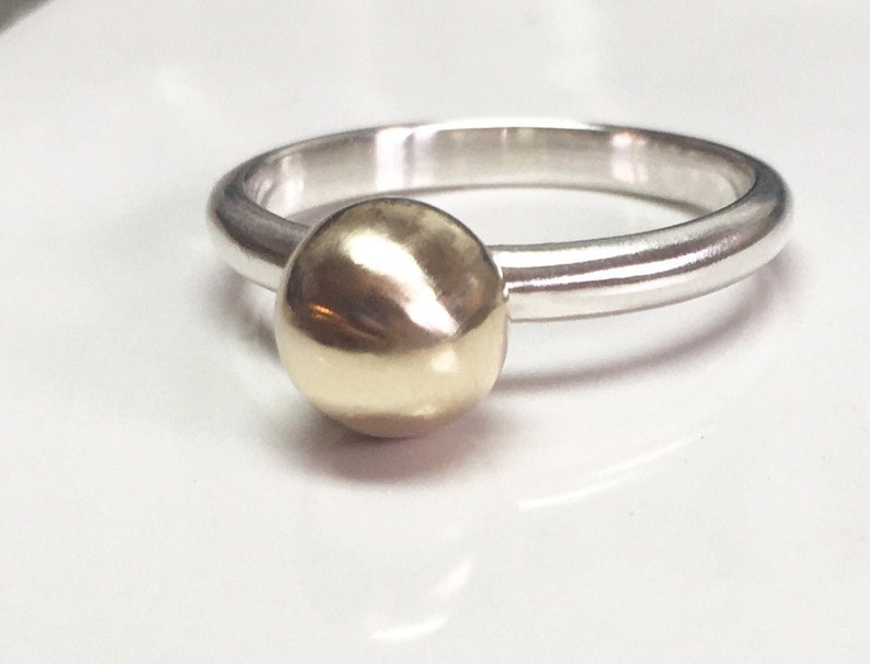 K&ouml;nnte beinhalten: Ein Silberring mit einer goldenen Kugel oben drauf.