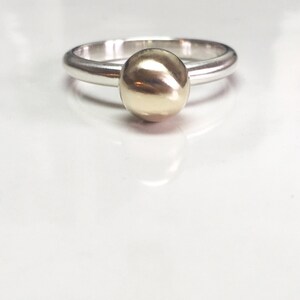 K&ouml;nnte beinhalten: Ein silberner Ring mit einer goldenen Kugel oben drauf.