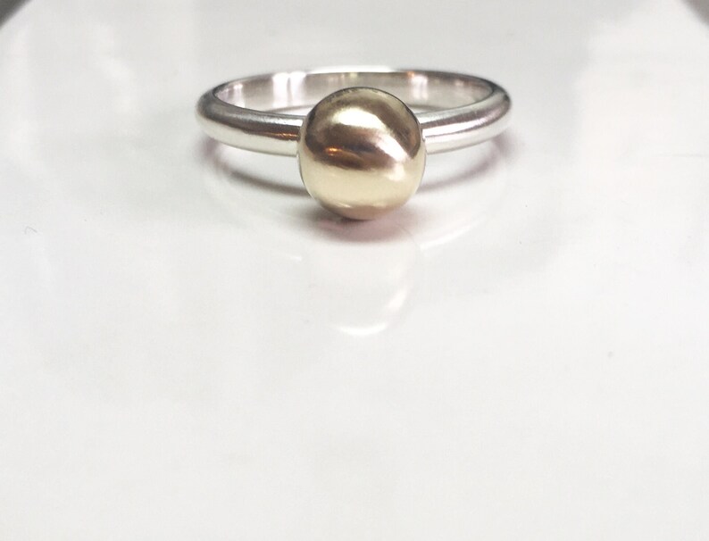 K&ouml;nnte beinhalten: Ein silberner Ring mit einer goldenen Kugel oben drauf.