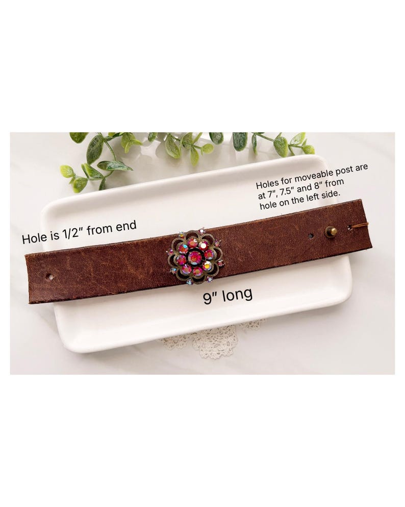 Pu&ograve; includere: Un bracciale in pelle marrone con un ornamento centrale a forma di fiore con cristalli iridescenti rosa e trasparenti. Il bracciale &egrave; lungo 9 pollici, con un foro a 1/2 pollice dall'estremit&agrave; e fori per un perno mobile a 7, 7,5 e 8 pollici.