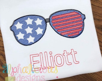 May include: White sweatshirt with red, white, and blue embroidered sunglasses and the name "Elliott" in red.