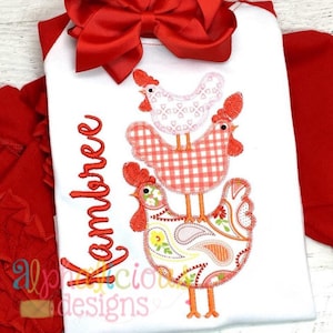 May include: White onesie with a red bow, a red, white, and pink embroidered design of three stacked chickens, and the name "Kambree" embroidered in green.