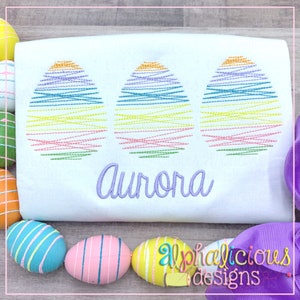 May include: White t-shirt with three colorful embroidered eggs and the name "Aurora" embroidered below. The shirt is surrounded by colorful Easter eggs.