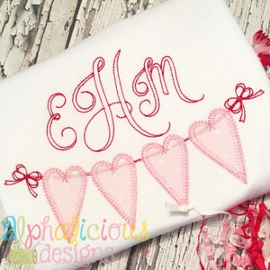 May include: White fabric with red embroidered initials and a banner of pink heart shapes. Each heart has a dotted pattern and is connected by a red thread. The word "Alphalicious designs" is printed in a colorful font.