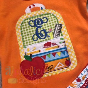 May include: A yellow, green, and red embroidered backpack with a white pocket and a red apple. The backpack has a white pocket with a ruler, pencils, and a pencil sharpener. The letter "E" is embroidered on the front of the backpack.