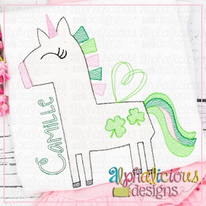 May include: A white unicorn with a green and pink mane and tail. The unicorn has a heart-shaped halo and three shamrocks on its side. The unicorn's name, "Camille", is embroidered on its side.