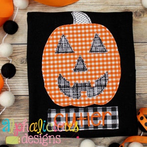 Peut inclure: T-shirt noir avec une applique de citrouille en vichy orange et blanc. La citrouille a un visage cousu noir avec un large sourire et des yeux triangulaires. Le texte "Cutter" est cousu en noir sur une bannière en vichy noir et blanc sous la citrouille.