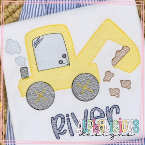 May include: A yellow embroidered design of a toy excavator with a brown dirt pile and the name "River" in blue script. The text "Alphalicious Designs" is also embroidered in rainbow colors.