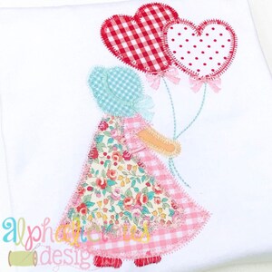 May include: A girl doll with a floral dress and a pink and white gingham skirt holds two red heart-shaped balloons. One balloon has a red and white gingham pattern and the other has red polka dots.