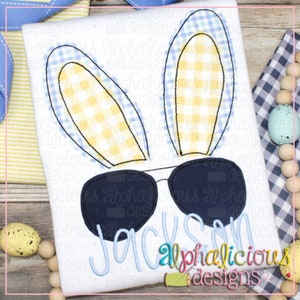May include: Embroidered design of a bunny wearing sunglasses with the name "Jackson" underneath. The bunny has blue and yellow checkered ears.