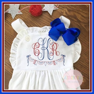 May include: White sleeveless dress with a red, white, and blue embroidered monogram and bunting. The monogram is "EKA".