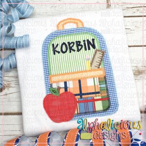 May include: A blue and green backpack with a red apple, a pencil, and a ruler. The backpack has a name tag that says "KORBIN".