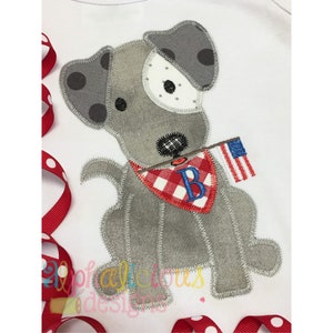 Può includere: Un cane grigio e bianco con pois neri che tiene una piccola bandiera americana. Il cane indossa un bandana a scacchi rosso e bianco con una lettera "B" blu ricamata.
