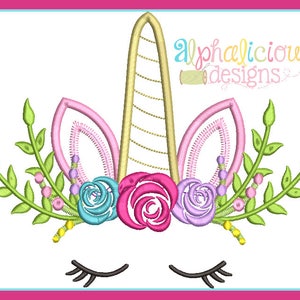Puede incluir: Diseño bordado de una cabeza de unicornio con los ojos cerrados, un cuerno dorado, orejas rosas y una corona floral con flores rosas, moradas, azules y amarillas.