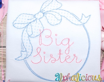 May include: Embroidered design of a blue and white polka dot bow with a blue ribbon around a circle with the text "Big Sister" in pink thread.