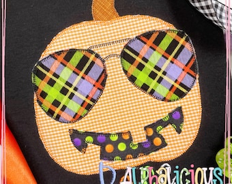 Könnte beinhalten: Ein schwarzes T-Shirt mit einer orangefarbenen Kürbis-Applikation. Der Kürbis hat ein kariertem Muster auf der Sonnenbrille und Punkten auf dem Mund. Der Text "Alphalicious Designs" ist unten auf dem Shirt gestickt.