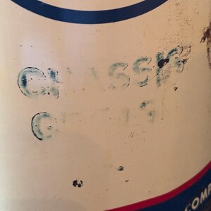 May include: Close-up of a vintage oil can with a white background, featuring blue and red accents. The word "CLASSIC" is stenciled in blue. The can has a blue and red border, with partial text visible at the bottom.