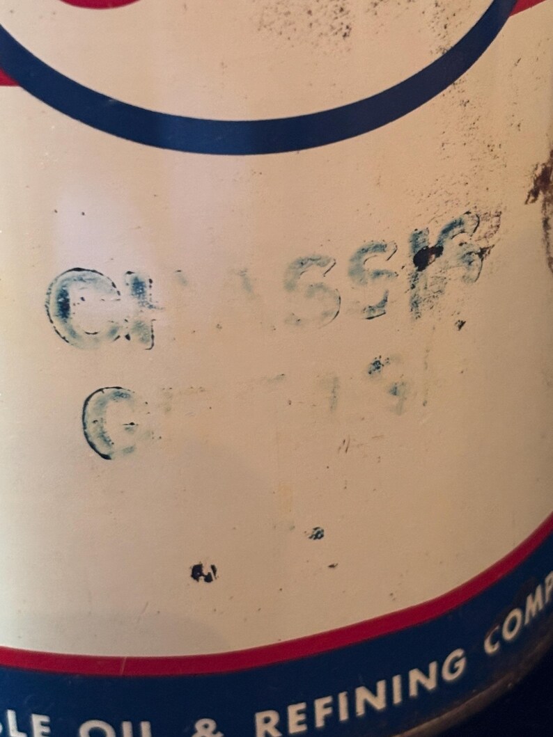 May include: Close-up of a vintage oil can with a white background, featuring blue and red accents. The word "CLASSIC" is stenciled in blue. The can has a blue and red border, with partial text visible at the bottom.