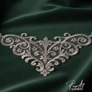 Può includere: Un'applicazione in pizzo ricamato color argento con un design ornato e simmetrico. L'applicazione presenta dettagli floreali e a volute. È ambientata su uno sfondo di tessuto verde scuro. L'immagine è firmata "Rinus Art Embroidery".