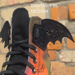 May include: A high-top sneaker featuring black laces and iridescent orange and yellow material, adorned with black embroidered bat wing attachments on the sides. The text DIGITAL FSL DESIGN is visible at the top of the image.