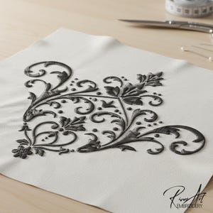 May include: A corner embroidery design in dark gray on a white fabric. The design features swirling floral and leaf patterns. Scissors, pins, and a measuring tape are in the background. The text "Rinus Art Embroidery" is in the lower right corner.